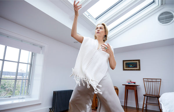 Taryn Toomey gesturing in a bright room, wearing a white poncho