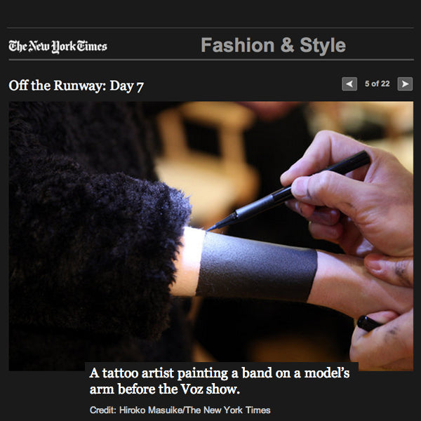 A tattoo artist painting a band on a model's arm before the Voz show.