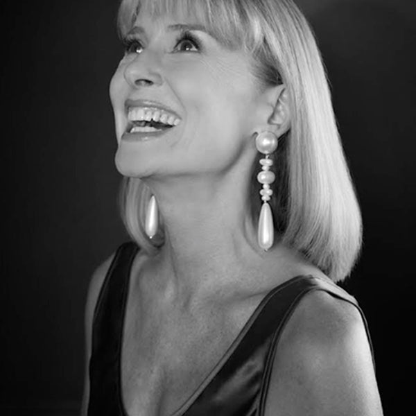 A woman smiling with earrings, expressing joy.