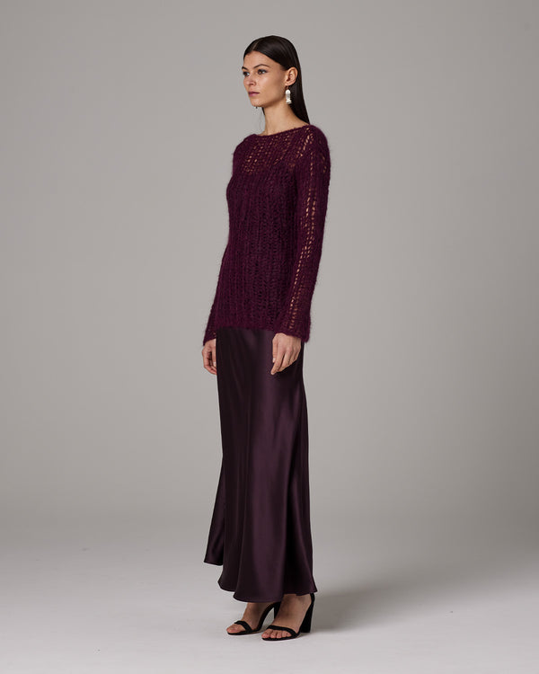 Model wearing a burgundy Open Mesh Boatneck Sweater with a long satin skirt