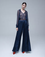 Model wearing a sheer bishop sleeve blouse with navy palazzo pants and red heels