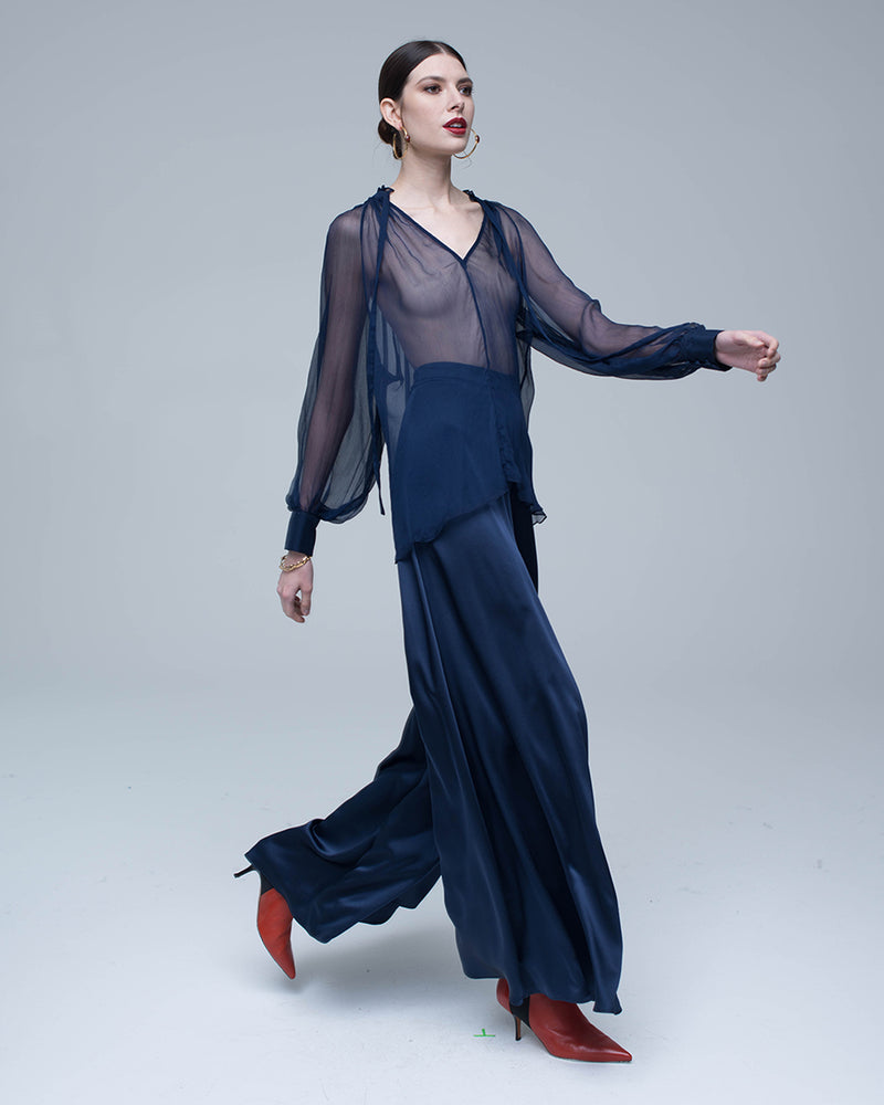 Model wearing a navy Bishop Sleeve Blouse in Crinkle Chiffon with wide-leg pants and red heels