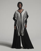 Model wearing a black and ivory poncho with geometric patterns
