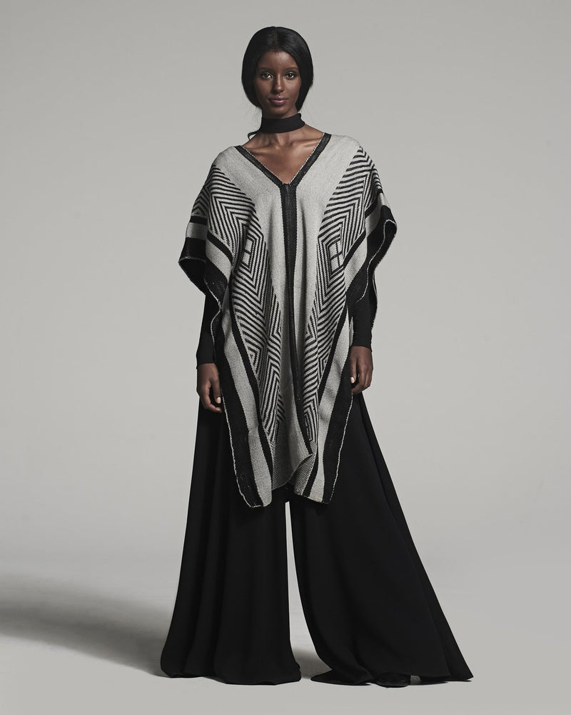Model wearing a black and ivory poncho with geometric patterns