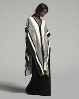 Model wearing a black and ivory poncho with geometric patterns
