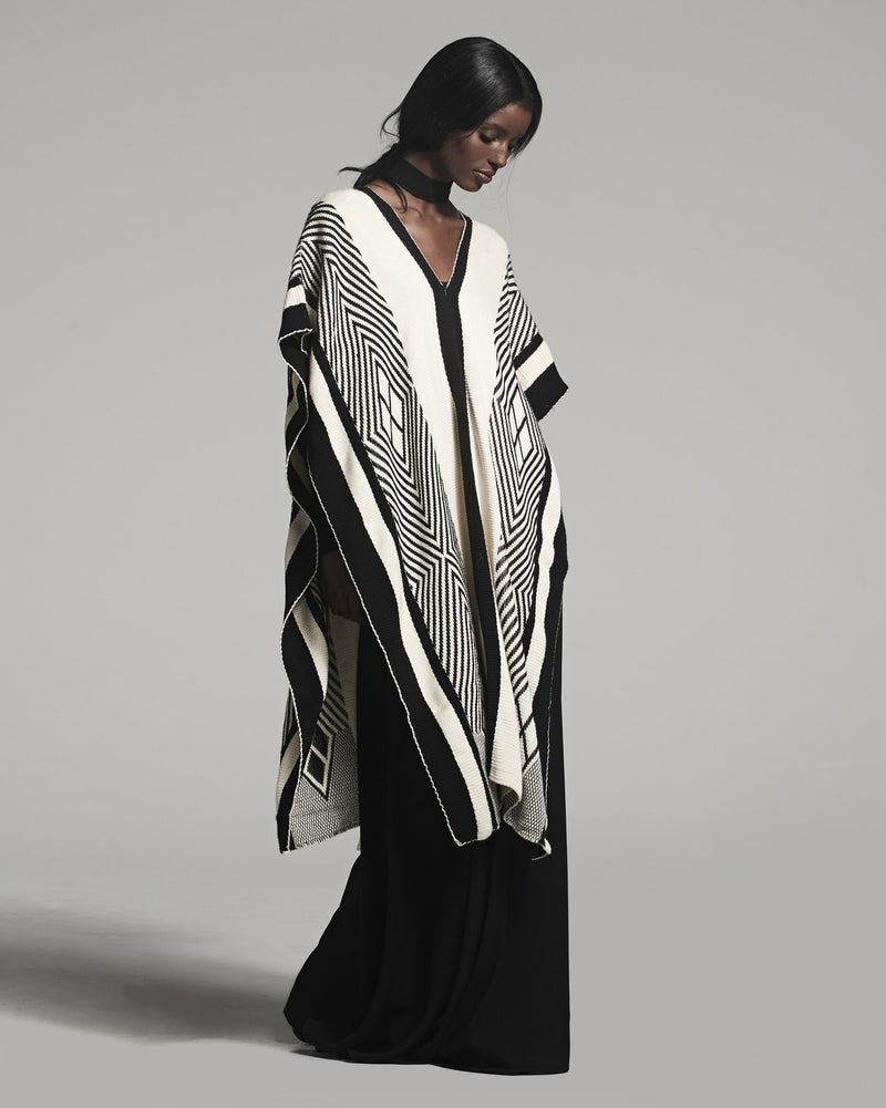 Model wearing a black and ivory poncho with geometric patterns