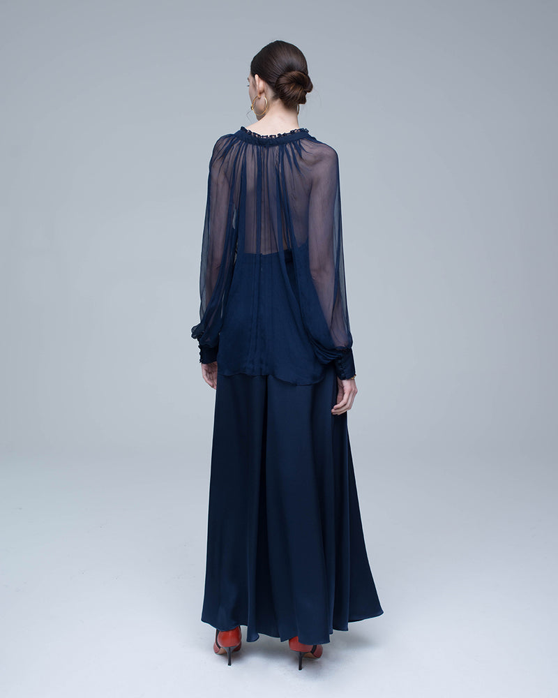 Model wearing a navy Bishop Sleeve Blouse with voluminous sleeves and a tie at the neck, paired with a long skirt.